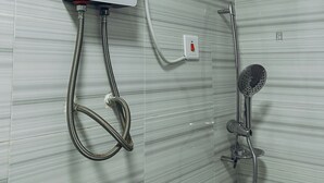 A bathroom with a TUK water heater, a handheld showerhead, and a wall-mounted control panel. - ZOHZEE GUEST HOUSE (Tema)