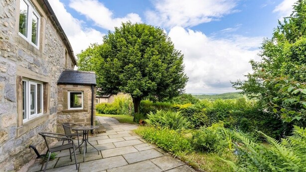 A stone building with a patio area featuring outdoor furniture.