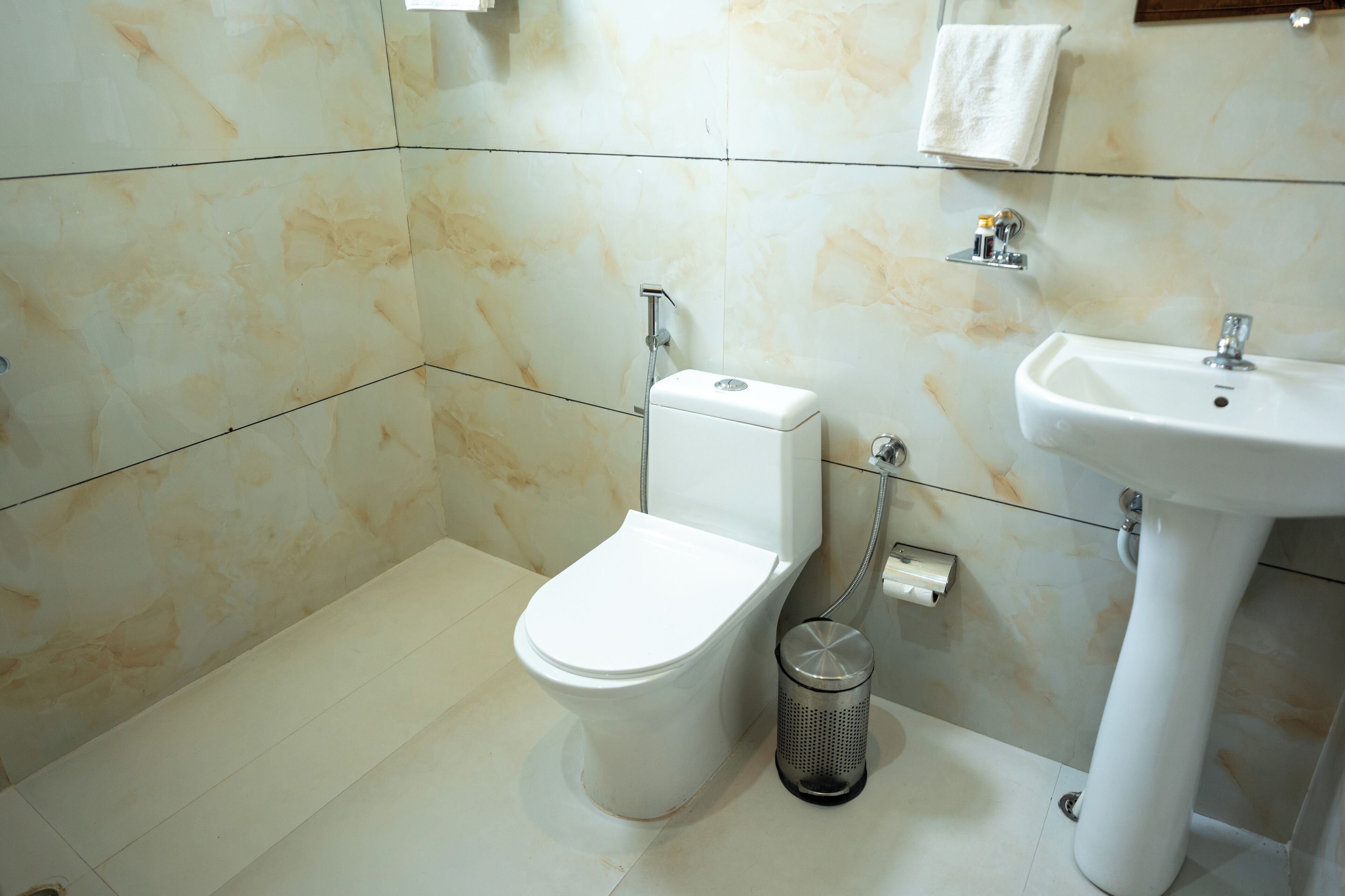 Une salle de bain avec des toilettes, un lavabo et une poubelle.