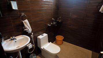 A bathroom with a white sink, toilet, and orange bucket.