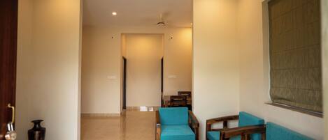 A spacious living area with a sofa, chairs, a coffee table, and a potted plant.