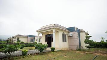 A residential building with a covered entrance, a small garden area with plants, and a visible water pipe.