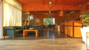 A wooden-paneled room with a green sofa, wooden coffee table, and a kitchen area with a counter and cabinets. - Aanandam Resort and Spa Pushkar (Pushkar)