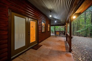Eine überdachte Veranda mit Holzwänden und Blick auf einen Wald.