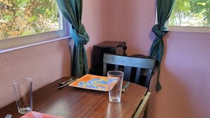 Una mesa de comedor con un mantel individual colorido, una copa, cubiertos y una silla.