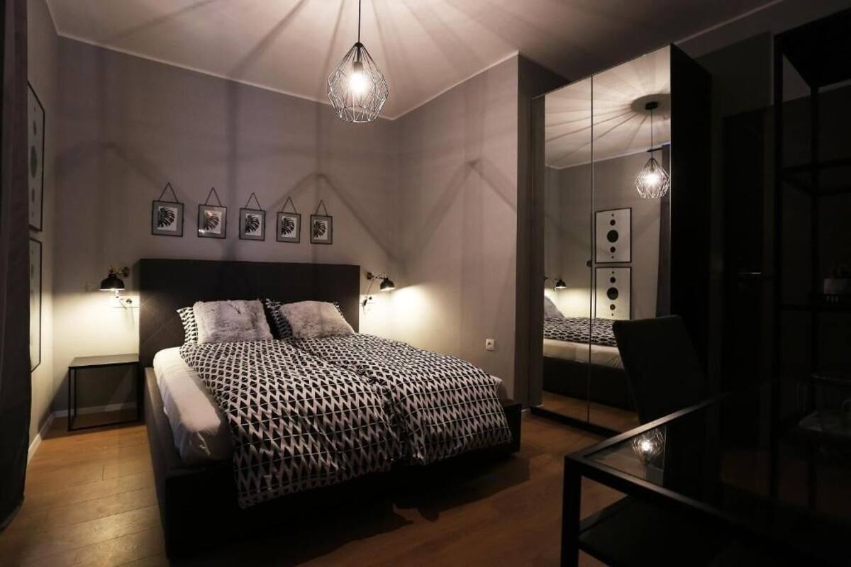 Une chambre moderne avec un lit, des lampes de chevet, un miroir et un luminaire suspendu.