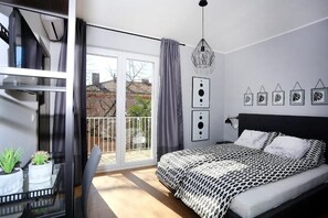 Un dormitorio moderno con una cama grande, un balcón con vistas y un área de comedor con plantas.