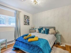 Une chambre à coucher avec un lit, une table de chevet, une fenêtre et un radiateur.