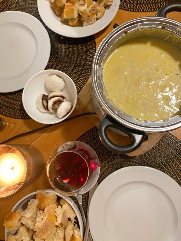 A dining table with a pot of soup, a bowl of mushrooms, a glass of red wine, and a candle. - Chalet Joue du Loup – Sleeps 6–7 (Le Dévoluy)