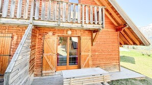 Eine Holzhütte mit Balkon, einer Holterrasse und einer Tür mit Glasscheiben.