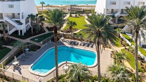 A resort with a swimming pool, palm trees, and a view of the ocean.