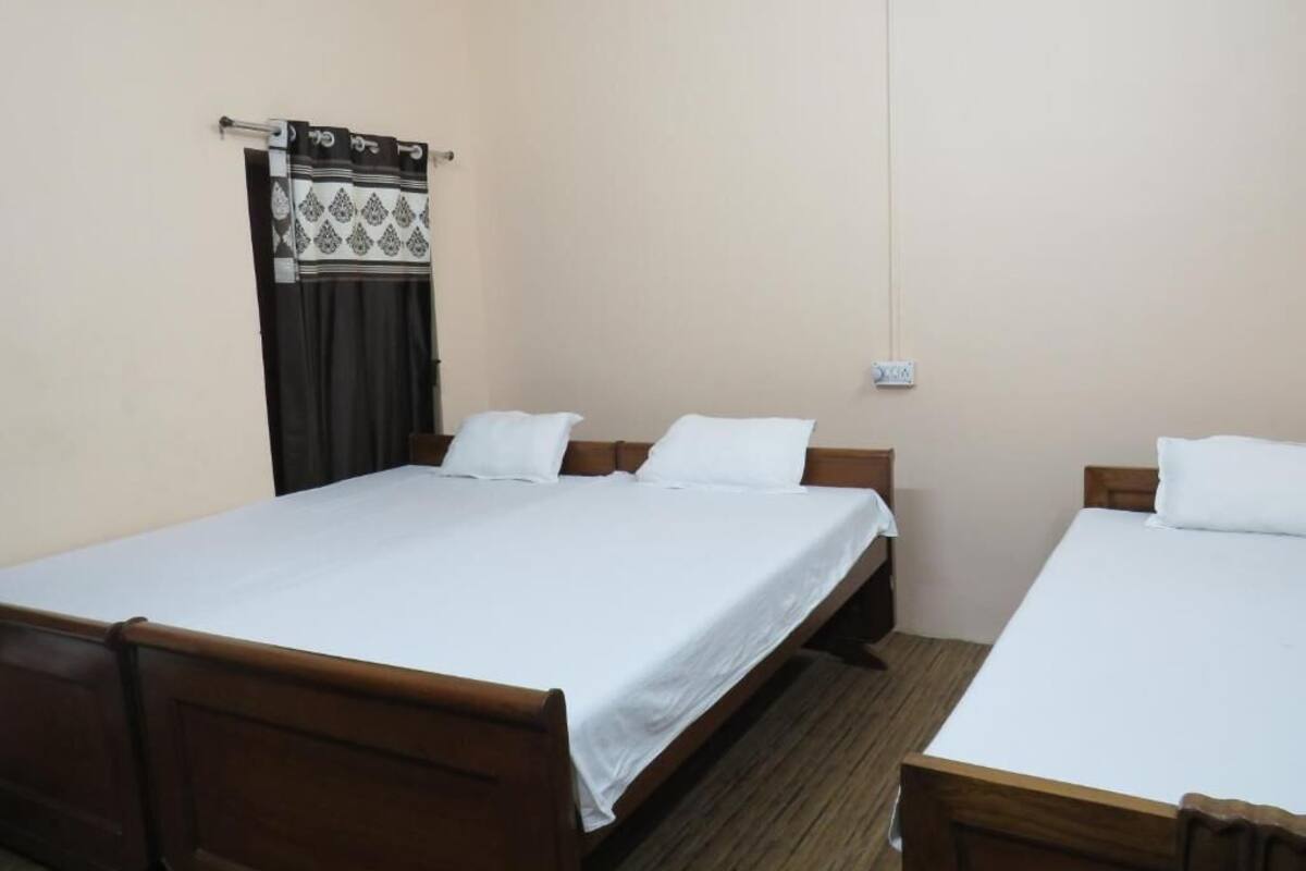 A room with two single beds, wooden headboards, and a window with a curtain.