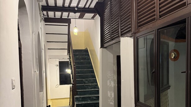 A hallway with a marble staircase, wooden beams, and a decorative glass door. - SHAW GUEST HOUSE (Kolkata)