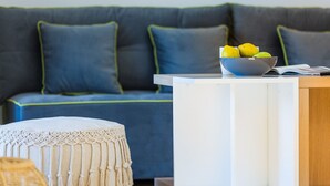 A modern living room with a grey sofa, a white side table, and a macrame ottoman.