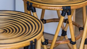 A white table with a magazine, a wicker basket, and two wicker stools.