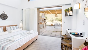 A modern hotel room with a bed, a desk, and a view of the outdoor patio.
