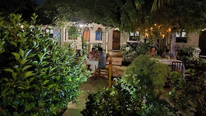 An outdoor dining area with tables, chairs, and string lights. - Ellavita Cottages (Nungwi)
