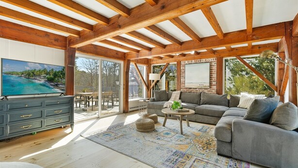 A spacious living room with a large gray sectional sofa, a coffee table, and a TV on a wooden cabinet. - 5-Bedroom Vacation Haven with Pool! (Brewster)