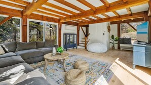 A spacious living area with a wooden ceiling, a gray sofa, a coffee table, and a patterned rug. - 5-Bedroom Vacation Haven with Pool! (Brewster)