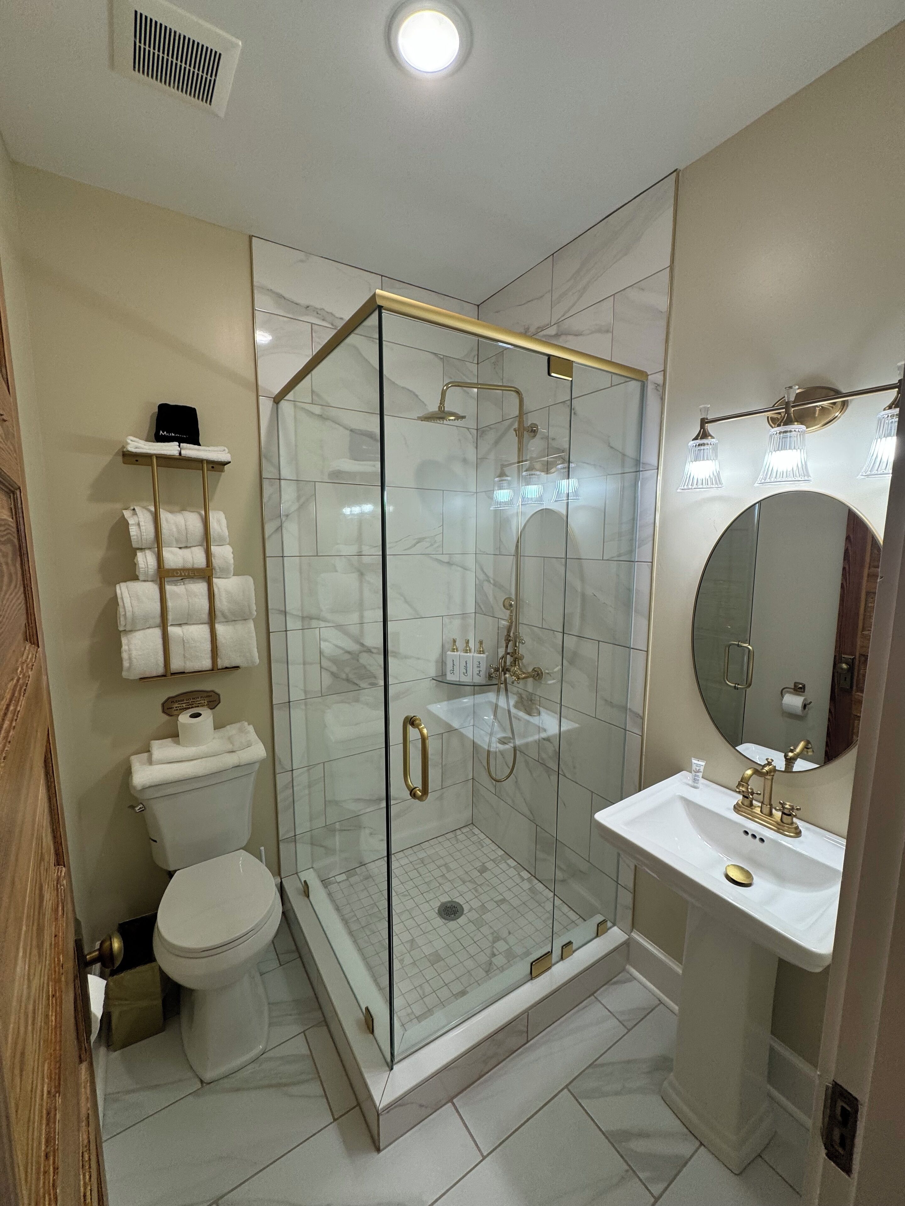 Un baño moderno con ducha de vidrio, lavamanos blanco y retrete.