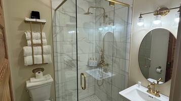 Un baño moderno con ducha de vidrio, lavamanos blanco y retrete.