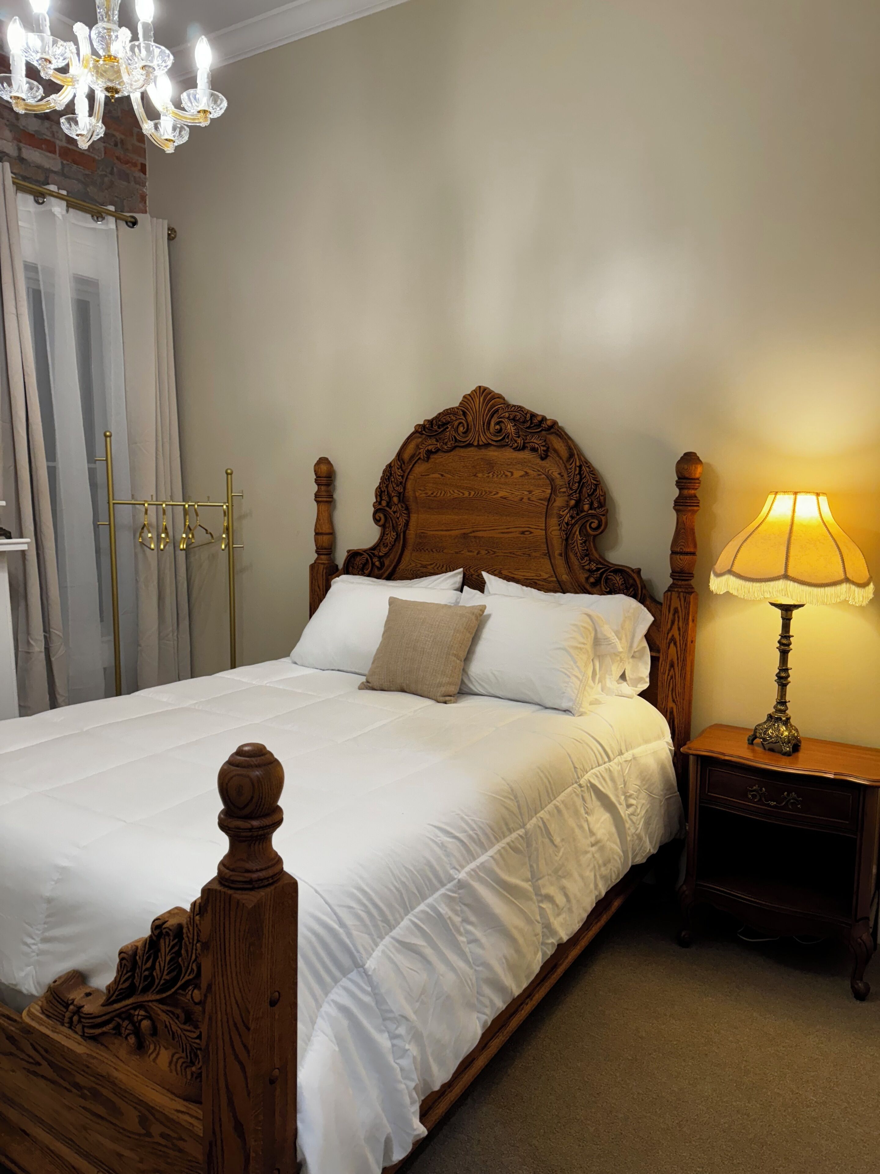 A neatly made bed with a wooden headboard, a bedside lamp, and a chandelier.