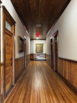 Un pasillo con suelos y paredes de madera, un banco central y cuadros enmarcados en las paredes.