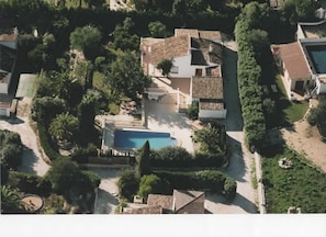 An aerial view of a residential area with multiple houses, a swimming pool, and surrounding greenery.
