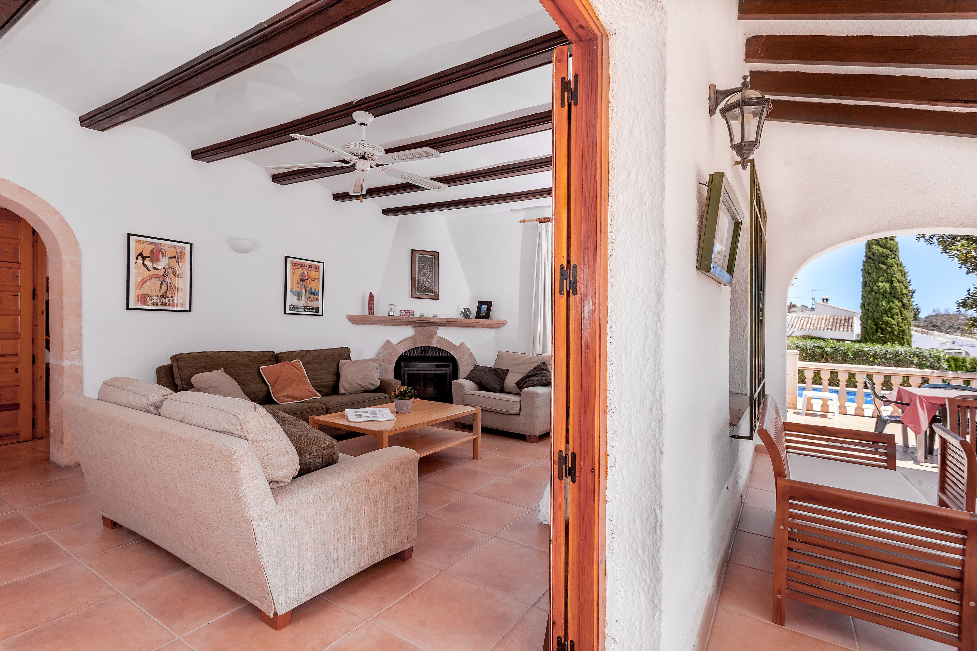 Ein Wohnzimmer mit Kamin, zwei Sofas, einem Couchtisch und einem Balkon mit Gartenmöbeln.