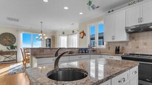 A kitchen with white cabinets, a granite countertop, and a stainless steel sink. - One More Day Caswell: Oceanfront Home With Elevator (Oak Island)