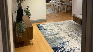 Ein zeitgemäßer Essbereich mit Holztisch und Stühlen, einem dekorativen Teppich und einer an der Wand befestigten Pflanze.