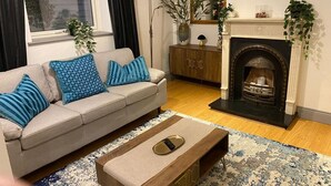 Ein Wohnzimmer mit einer Couch, einem Couchtisch, einem Kamin und Zierpflanzen.
