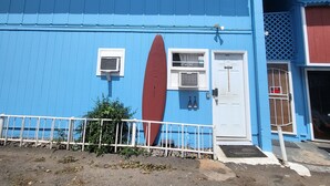 A blue building with a surfboard mural, a white door, and a small window. - Budget Downtown Studio-G w/Queen Bed,  Micro-Kitchen AC, WIFI & 4 free Streamers (Wailuku)