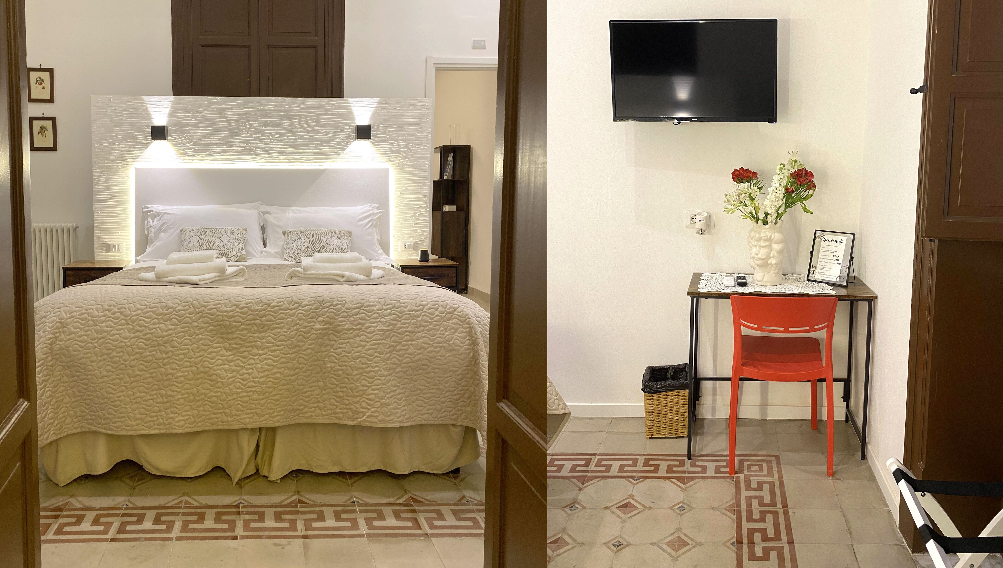 A hotel room with a bed, bedside lamps, a TV, a desk with a chair, and a vase with flowers.