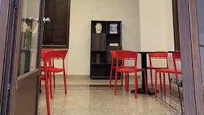 Una habitación con suelo estampado, una araña, un armario de madera oscura y sillas rojas.