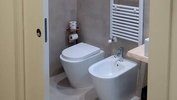 A modern bathroom with a toilet, bidet, and sink.