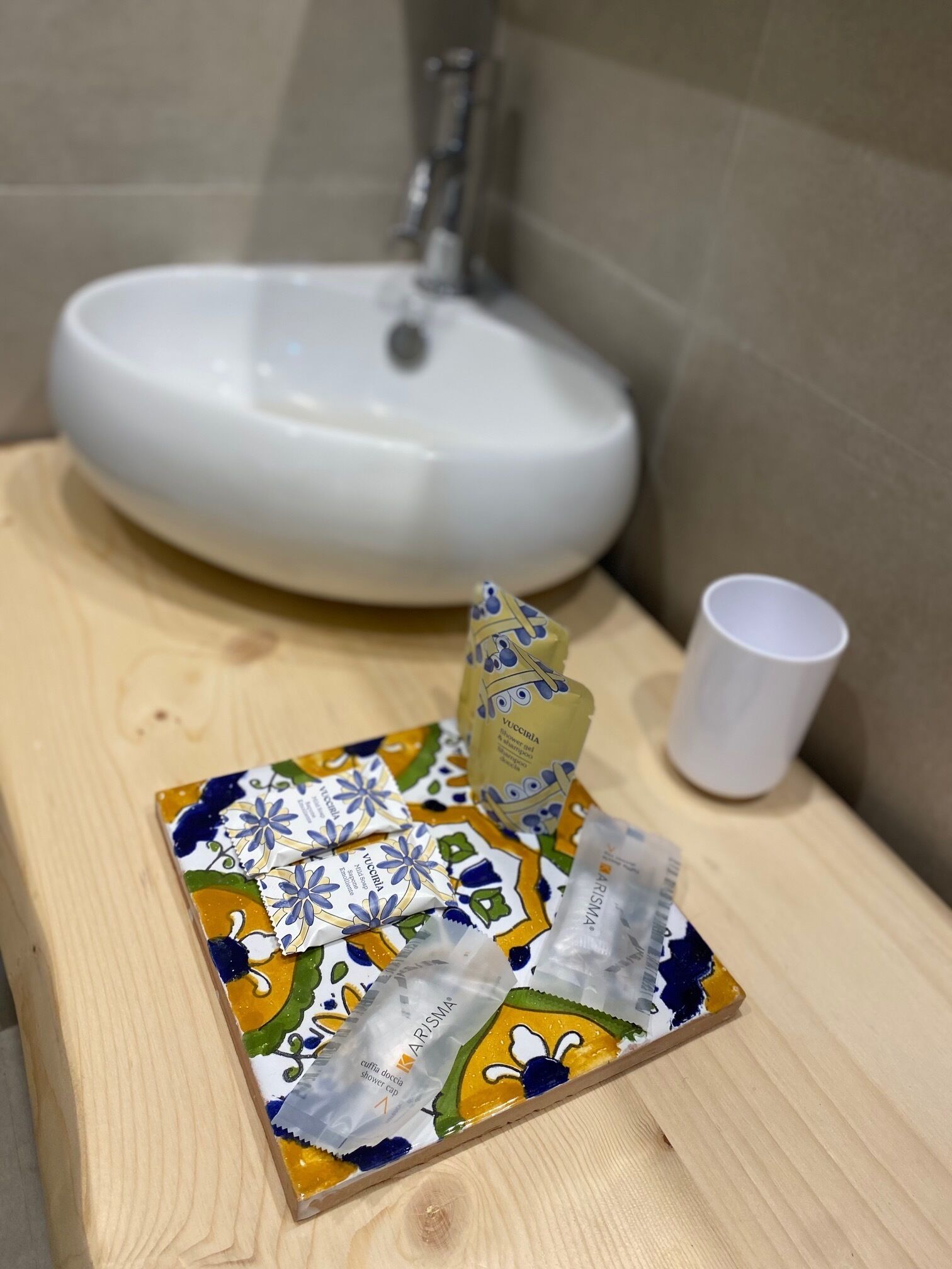 A bathroom sink with a cup and a decorative item on a wooden surface.