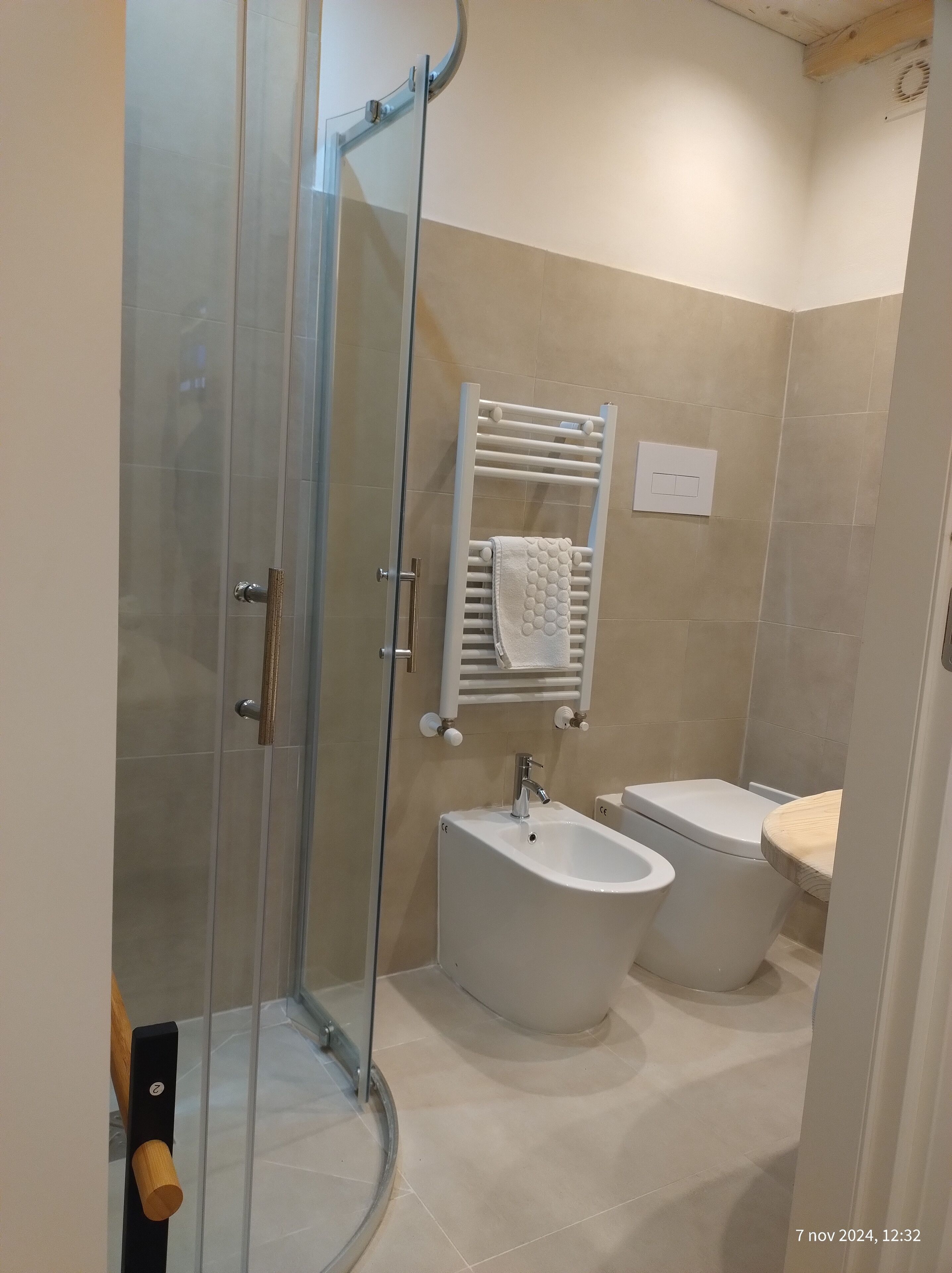 A modern bathroom with a glass shower enclosure, a bidet, and a toilet.