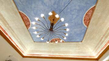 A ceiling with a central chandelier and decorative moldings.