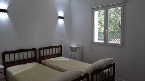 A bedroom with two single beds, a nightstand, a small cabinet, and a window with a view of greenery outside. - Verdon region, house with terrace and garden, 3 bdrms, discount/2nd week (Régusse)