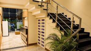 A modern interior with a staircase, a refrigerator, a wooden cabinet, and a potted plant. - Hotel Shivaay  (Indore)