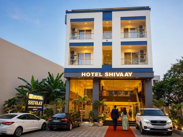 A hotel with a modern facade, multiple balconies, and a red carpet leading to the entrance. - Hotel Shivaay  (Indore)