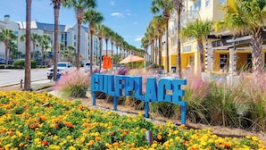 A street sign with 'GULFPLACE' in the foreground, surrounded by colorful flowers and palm trees. - Golf Cart Included, 3 Pools, Steps to Beach, Pickleball (Santa Rosa Beach)