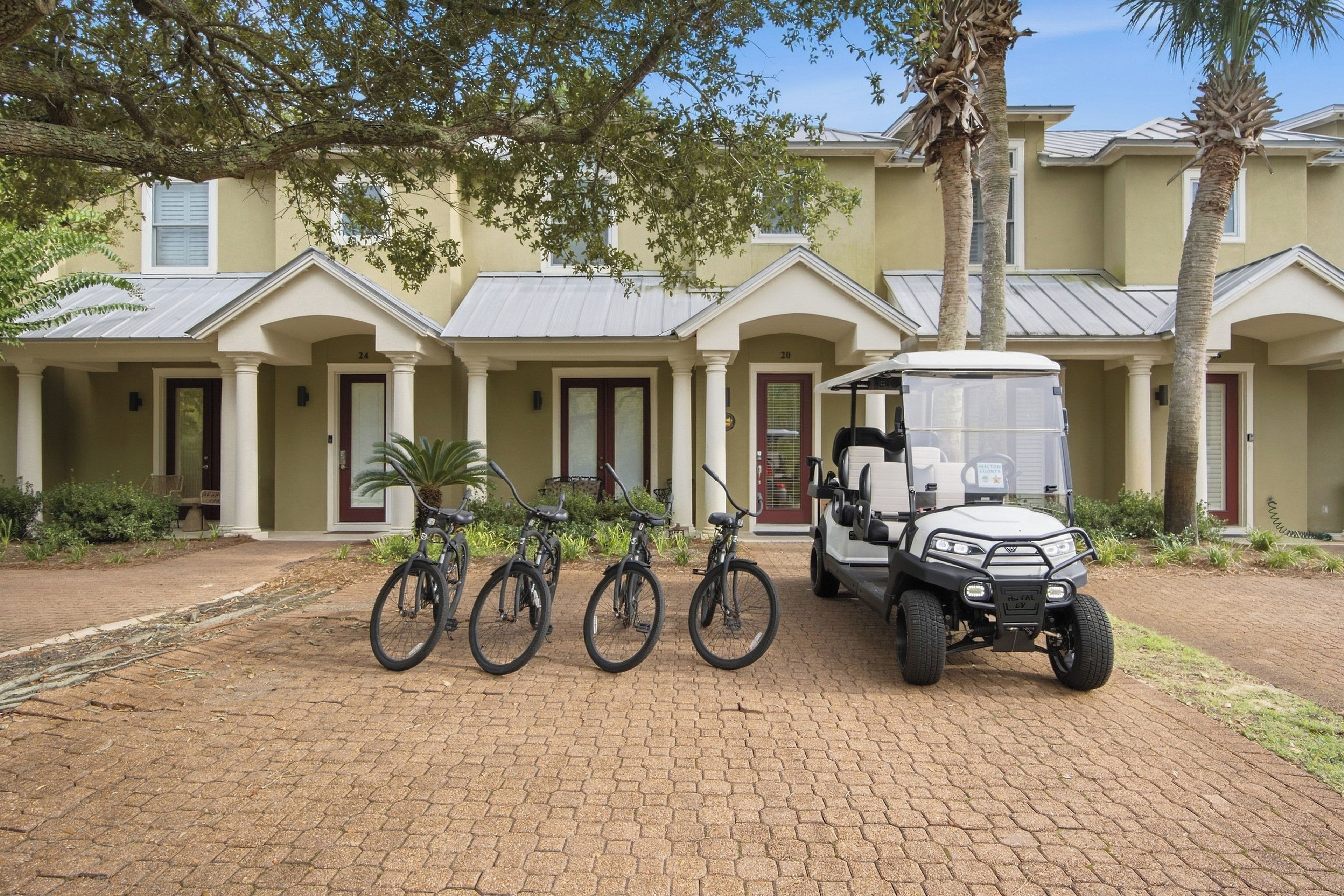 Un bâtiment avec une allée pavée, trois vélos et une voiturette de golf.
