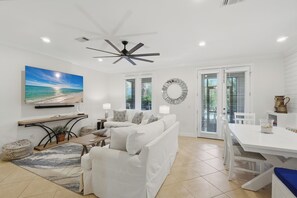 A modern living room with a white sofa, a dining table, and a ceiling fan.
