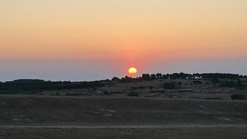 A sunset over a hilly landscape with a stone wall in the foreground.