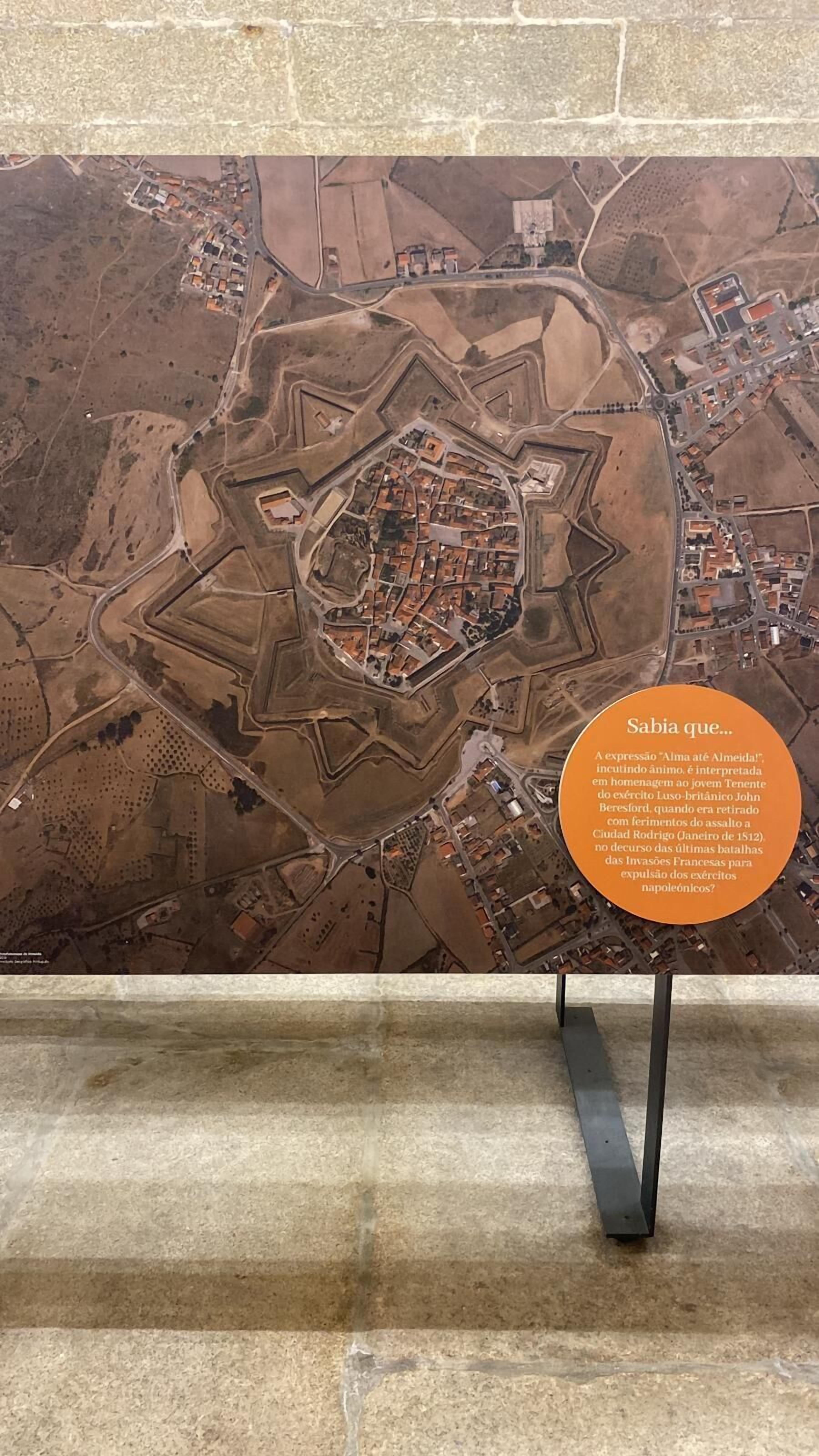 Un mapa histórico que muestra una estructura central fortificada rodeada de edificios más pequeños, indicando la disposición de una ciudad amurallada.
