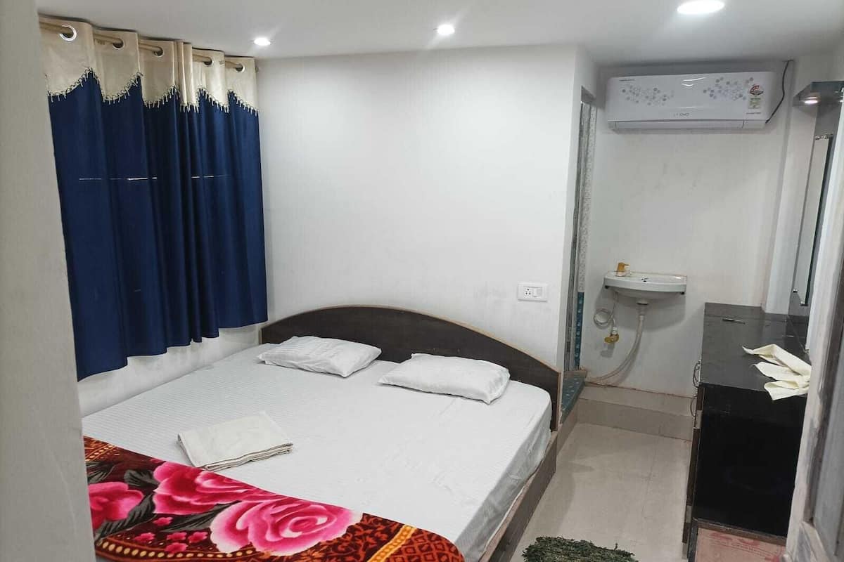 Ein Schlafzimmer mit Bett, Nachttisch, kleinem Waschbecken und Klimaanlage.