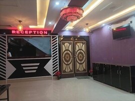 Un área de recepción con diseño moderno, que incluye un mostrador de recepción, puertas dobles con diseños decorativos y una araña.