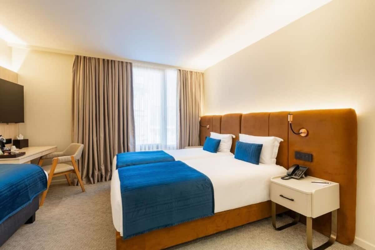 A hotel room with a large bed, a desk, a chair, and a TV.